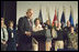 With Mrs. Laura Bush looking on, President George W. Bush addresses military medical caregivers Wednesday, Dec. 21, 2005, before visiting with the wounded at the National Naval Medical Center in Bethesda, Md. The President told the caregivers, "... On behalf of a grateful nation, thanks for doing your duty, thanks for serving, thanks for being an important part of this march for freedom; and thanks, most of all, for bringing comfort and aid and solace to those who have been hurt on the battlefield and their families."