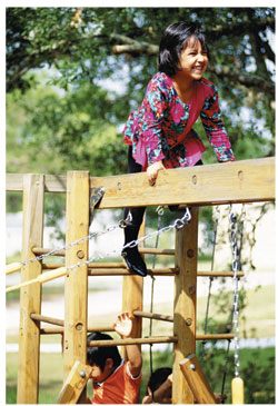 girl playing on wooden playground equipment