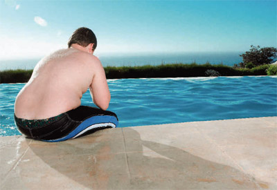 overweight boy sitting by swimming pool