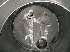 Two USRA technicians at NASA Ames Research Center are reflected in the coated SOFIA telescope main mirror.