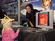 Darlene Mendoza of NASA's Ames Research Center shows a young visitor at NASA's SOFIA exhibit what she looks like through the lens of an infrared camera at the International Balloon Fiesta.