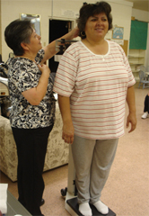 Promotora Blanca Robles measures the height and weight of Pasos Adelante participant Maria Arballo.