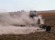 Photograph ofa heavy agricultural machine enveloped in dust
