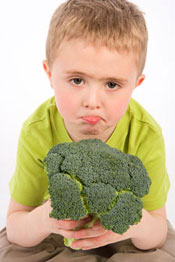 photo of a frowning boy holding brocoli