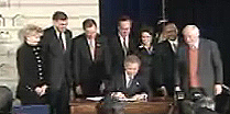 Watching President Bush sign into law the American Dream Downpayment Act are, from left to right, Delegate Madeleine Bordallo, Guam; former HUD Secretary Mel Martinez; Rep. Michael Oxley, Ohio; Sen. Wayne Allard, Colorado; Rep. Katherine Harris, Florida; Acting HUD Secretary Jackson; and Rep. Jim Leach, Iowa.