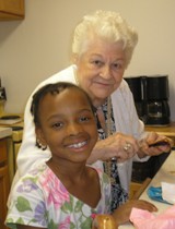 [Photo: Staff member Gloria Weldon helps a young resident prepare a snack.]