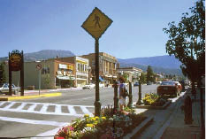 Photo shows a pedestrian crossing of a wide Main street in a historic western town.