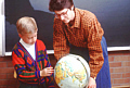 Teacher and child pointing to a globe during tutoring available at the Clinical Center.
