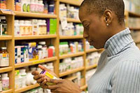Image of woman looking at pill bottle in store aisle.