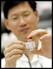 Photo of a pharmacist placing a label on a small glass bottle.