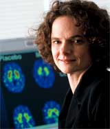 Photo of NIDA Director Nora Volkow in front of computer screen displaying PET scans