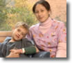 A photo of a nurse sitting next to a patient that is a child.