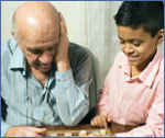 Photo of an older man playing chess with a child