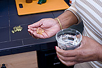 Woman holding dietary supplements in the one hand and a glass of water in the other.