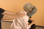 A woman receives seated massage.