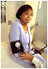 Middle-aged African American woman having her blood pressure taken by a health care provider.