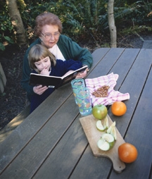 older person reading to child while sharing an apple