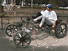 Two people riding a moonbuggy over a mound of rocks