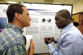 Gunnar Kwakye (r), a 2006 University of Maryland-Eastern Shore graduate, shows his poster "The Effects of Ketogenic Diet on Gliogenosis Following Neuronal Injury" to poster judge Dr. Robert Brosh, Jr., of the Laboratory of Molecular Gerontology.