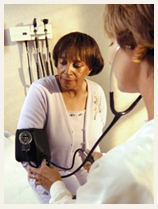 Health care professional taking an adult woman’s blood pressure.