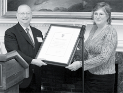 A photograph of Shelia Zahm receiving the Harvard Alumni of Merit Award from Dean Barry Bloom.