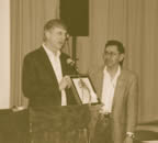 photo of Dr. Francis Collins presenting Dr. 
                      Don Denetdeal with a framed CD of human genome sequence