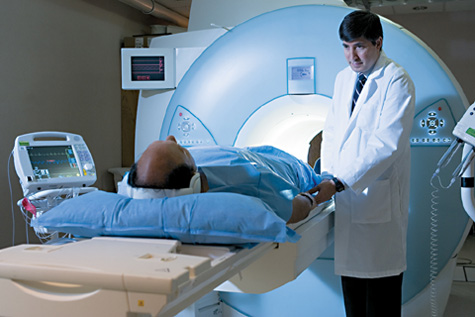 Photo showing a patient lying on a sliding table outside of a cardiac MRI machine