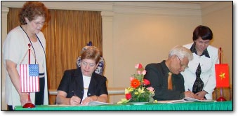 Dr. Anne Sassaman and Dr. Nguyen Ngoc Sinh signing the document