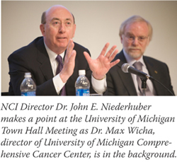 NCI Director Dr. John E. Niederhuber makes a point at the University of Michigan Town Hall Meeting as Dr. Max Wicha, director of University of Michigan Comprehensive Cancer Center, is in the background.