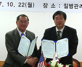 NIAAA director Dr. T.-K. Li (l) and Dr. Jong-Koo Lee, director general of the Korea Center for Disease Control and Prevention, hold copies of the letter of intent signed by both to increase cooperation in biomedical research between the two countries.