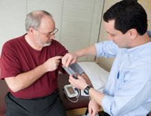 photo of a doctor taking the blood pressure of an older man.
