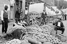 Photo: African-American vendors with farm produce--melons, corn and squash