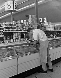 phto of a man bending over a freezer case inthe grocery store