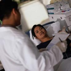 Fotografía de un profesional de la salud hablando con una mujer en una cama de hospital