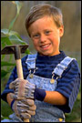 A boy holds a hoe while standing amid cornstalks