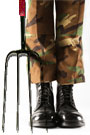 Close-up of a soldier's camoflauged pantlegs and black Army boots next to a pitchfork