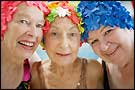 Close-up of three elderly women wearing colorful bathing caps
