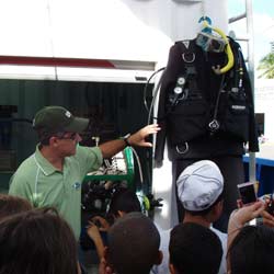 Crew member shows a wetsuit to kids
