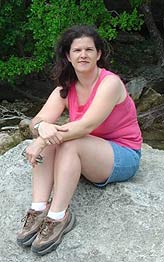 image of author sitting on a rock with woods in the background
