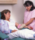 A woman in bed receiving care from a nurse