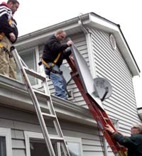 men raising solar panel to roof
