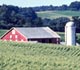 A field with a barn and silo in the background