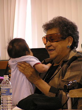 Smiling, older woman holding an infant in her arms.