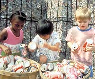 Photo: three children collecting soda cans for recycling.