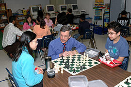 MMS employee showing two students how to play chess