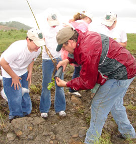 University of Kentucky professor helps a student from John’s Creek Elementary School, Pikeville, Ky., plant an American chestnut on a surface mine site near Meta, Ky.