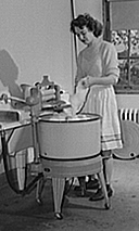 Woman washing clothes in a  wringer washing machine.