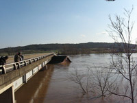 Image of house colliding with a bridge and roof being ripped off during a flood.