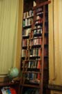 Ladder leaning on a tall bookshelf with books.