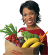 African American woman holding a grocery bag full of produce.